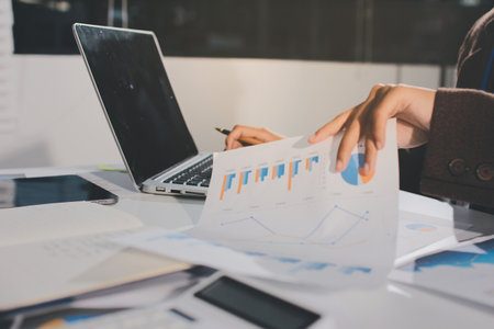 Focused young businessman signing agreement with skilled lawyer in eyeglasses. Concentrated financial advisor showing place for signature on paper contract document to male client at meeting in officeの写真素材