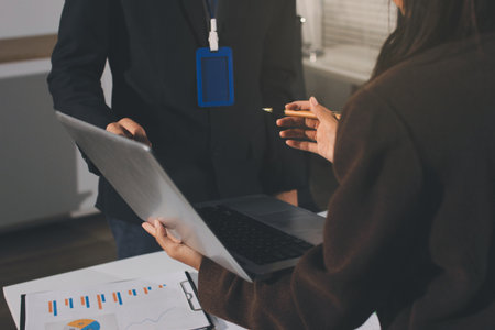 Focused young businessman signing agreement with skilled lawyer in eyeglasses. Concentrated financial advisor showing place for signature on paper contract document to male client at meeting in officeの写真素材
