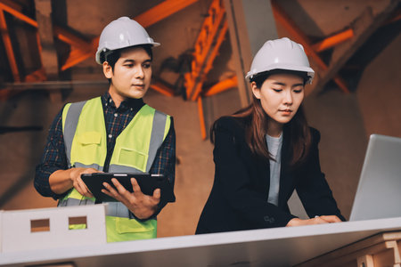 Construction manager and engineer dressed in hard helmets explore construction documentation on the building site near the steel framesの写真素材