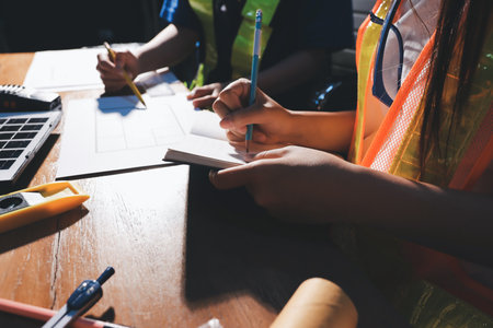 Closeup of team of industrial engineers meeting analyze machinery blueprints consult project on table in manufacturing factory. Working in manufacturing plant or production plant.の写真素材