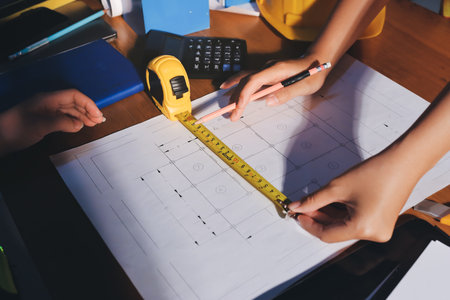 Closeup of team of industrial engineers meeting analyze machinery blueprints consult project on...