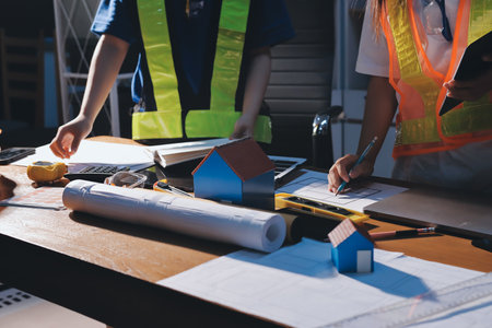 Closeup of team of industrial engineers meeting analyze machinery blueprints consult project on...
