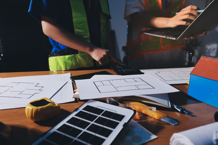 Closeup of team of industrial engineers meeting analyze machinery blueprints consult project on...
