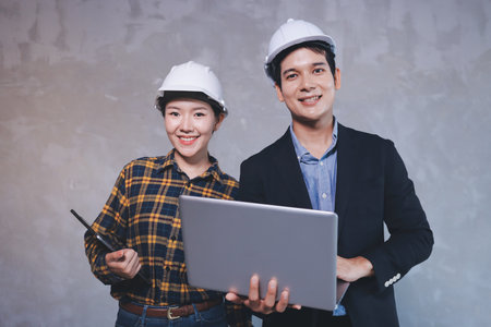 Construction manager and engineer dressed in orange work vests and hard helmets explore construction documentation on the building site near the steel framesの写真素材