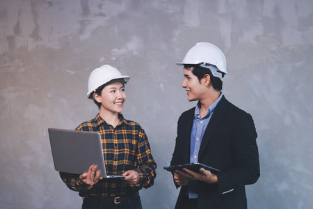 Construction manager and engineer dressed in hard helmets explore construction documentation on the...