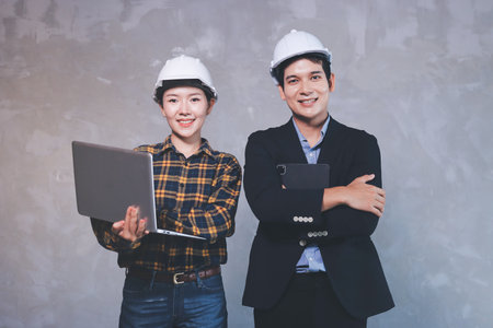 Construction manager and engineer dressed in hard helmets explore construction documentation on the building site near the steel framesの写真素材