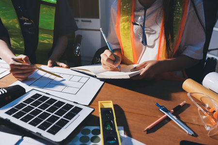 Closeup of team of industrial engineers meeting analyze machinery blueprints consult project on table in manufacturing factory. Working in manufacturing plant or production plant.の写真素材