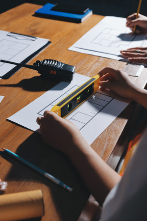 Closeup of team of industrial engineers meeting analyze machinery blueprints consult project on table in manufacturing factory. Working in manufacturing plant or production plant.の写真素材