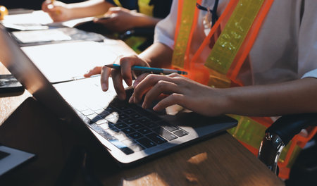 Closeup of team of industrial engineers meeting analyze machinery blueprints consult project on table in manufacturing factory. Working in manufacturing plant or production plant.の写真素材