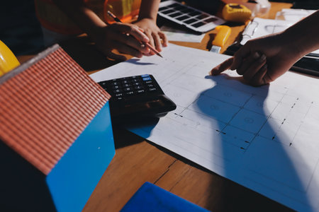 Closeup of team of industrial engineers meeting analyze machinery blueprints consult project on...
