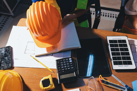 Closeup of team of industrial engineers meeting analyze machinery blueprints consult project on table in manufacturing factory. Working in manufacturing plant or production plant.の写真素材