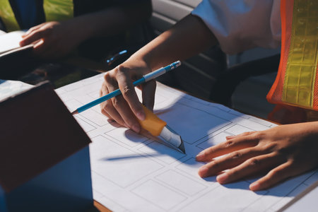 Closeup of team of industrial engineers meeting analyze machinery blueprints consult project on...