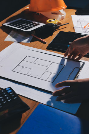 Closeup of team of industrial engineers meeting analyze machinery blueprints consult project on...