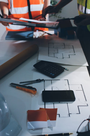Closeup of team of industrial engineers meeting analyze machinery blueprints consult project on table in manufacturing factory. Working in manufacturing plant or production plant.の写真素材