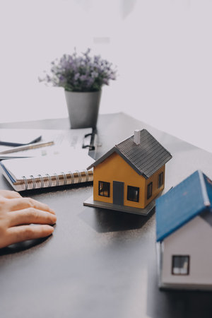 Real estate broker agent presenting and consult to customer to decision making sign insurance form agreement, buy and sell home model, concerning mortgage loan offer for and house insuranceの写真素材