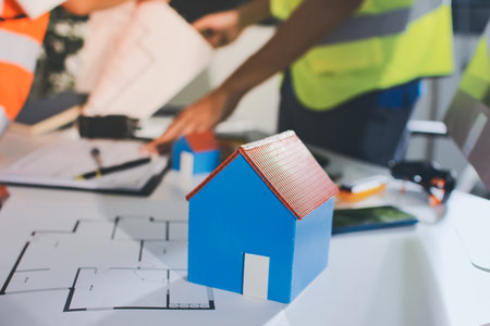 Closeup of team of engineers meeting analyze blueprints consult project on table in manufacturing factory. Working in manufacturing plant or production plant.の写真素材