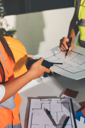 Closeup of team of industrial engineers meeting analyze machinery blueprints consult project on table in manufacturing factory. Working in manufacturing plant or production plant.の写真素材