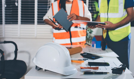 Closeup of team of industrial engineers meeting analyze machinery blueprints consult project on table in manufacturing factory. Working in manufacturing plant or production plant.の写真素材