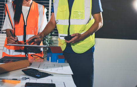 Closeup of team of industrial engineers meeting analyze machinery blueprints consult project on...