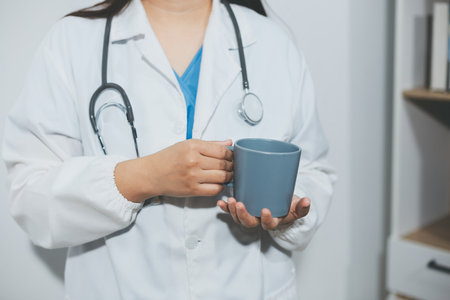 Portrait of doctor woman standing holding coffee cup in white studio backgroundの写真素材