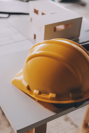 Construction manager and engineer dressed in orange work vests and hard helmets explore construction documentation on the building site near the steel framesの写真素材