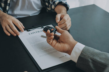 Car salesman gave the keys to the customers who signed the purchase contract legally, Successful completion of car sales, Purchase contract and key delivery.の写真素材
