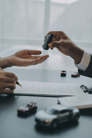 Car salesman gave the keys to the customers who signed the purchase contract legally, Successful completion of car sales, Purchase contract and key delivery.の写真素材