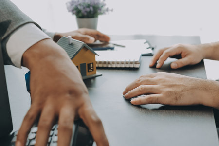 Real estate broker agent presenting and consult to customer to decision making sign insurance form agreement, buy and sell home model, concerning mortgage loan offer for and house insuranceの写真素材