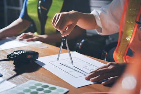 Closeup of team of industrial engineers meeting analyze machinery blueprints consult project on table in manufacturing factory. Working in manufacturing plant or production plant.の写真素材
