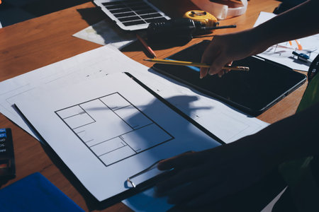 Closeup of team of industrial engineers meeting analyze machinery blueprints consult project on...