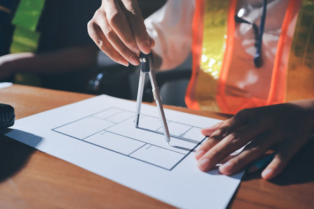 Closeup of team of industrial engineers meeting analyze machinery blueprints consult project on table in manufacturing factory. Working in manufacturing plant or production plant.の写真素材