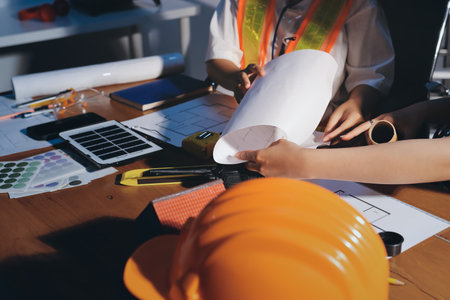 Closeup of team of industrial engineers meeting analyze machinery blueprints consult project on table in manufacturing factory. Working in manufacturing plant or production plant.の写真素材