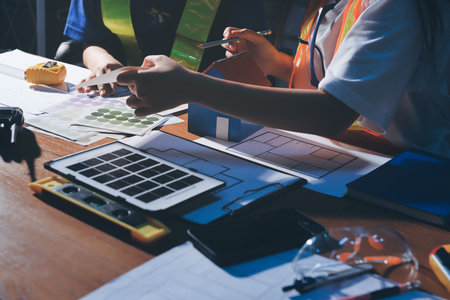 Closeup of team of industrial engineers meeting analyze machinery blueprints consult project on table in manufacturing factory. Working in manufacturing plant or production plant.の写真素材