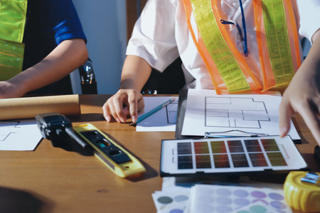 Closeup of team of industrial engineers meeting analyze machinery blueprints consult project on...
