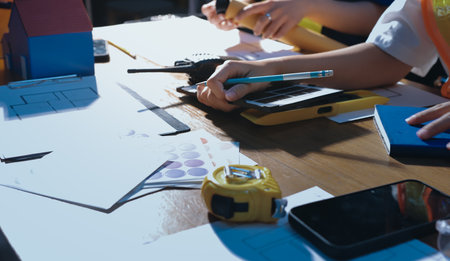 Closeup of team of industrial engineers meeting analyze machinery blueprints consult project on table in manufacturing factory. Working in manufacturing plant or production plant.の写真素材
