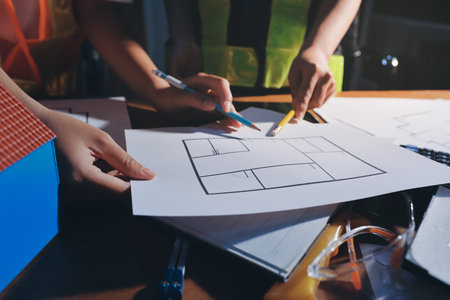Closeup of team of industrial engineers meeting analyze machinery blueprints consult project on table in manufacturing factory. Working in manufacturing plant or production plant.の写真素材