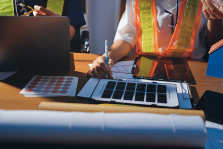 Closeup of team of industrial engineers meeting analyze machinery blueprints consult project on table in manufacturing factory. Working in manufacturing plant or production plant.の写真素材