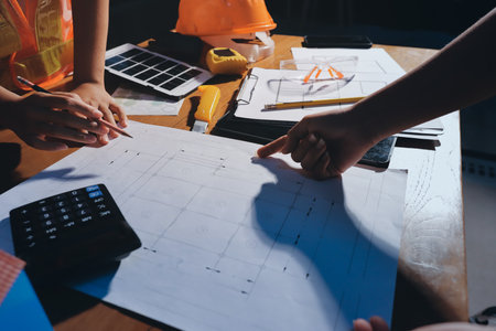 Closeup of team of industrial engineers meeting analyze machinery blueprints consult project on...