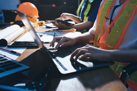 Closeup of team of industrial engineers meeting analyze machinery blueprints consult project on table in manufacturing factory. Working in manufacturing plant or production plant.の写真素材