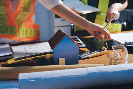 Close-up of team of engineers meeting to analyze blueprints and consult on a project on a table in...
