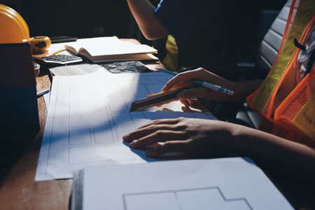 Closeup of team of industrial engineers meeting analyze machinery blueprints consult project on table in manufacturing factory. Working in manufacturing plant or production plant.の写真素材