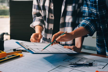 Construction and structure concept of engineer working drawing on blueprint meeting for project working with partner on model building and engineering tools in working site, construction concept.の写真素材