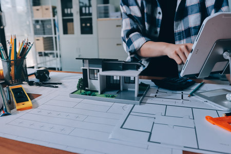 Construction and structure concept of engineer working drawing on blueprint meeting for project working with partner on model building and engineering tools in working site, construction concept.の写真素材