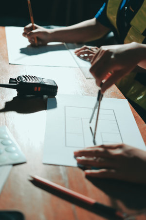 Closeup of team of industrial engineers meeting analyze machinery blueprints consult project on...
