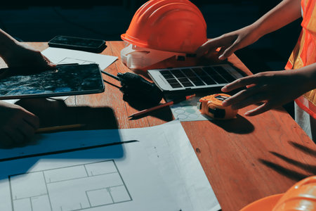 Closeup of team of industrial engineers meeting analyze machinery blueprints consult project on table in manufacturing factory. Working in manufacturing plant or production plant.の写真素材