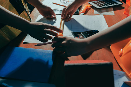 Closeup of team of industrial engineers meeting analyze machinery blueprints consult project on table in manufacturing factory. Working in manufacturing plant or production plant.の写真素材