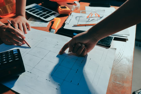 Closeup of team of industrial engineers meeting analyze machinery blueprints consult project on table in manufacturing factory. Working in manufacturing plant or production plant.の写真素材