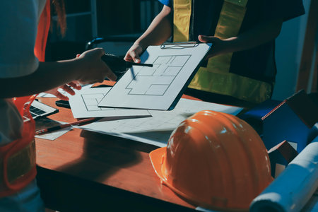 Closeup of team of industrial engineers meeting analyze machinery blueprints consult project on...