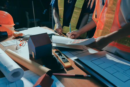 Closeup of team of industrial engineers meeting analyze machinery blueprints consult project on table in manufacturing factory. Working in manufacturing plant or production plant.の写真素材