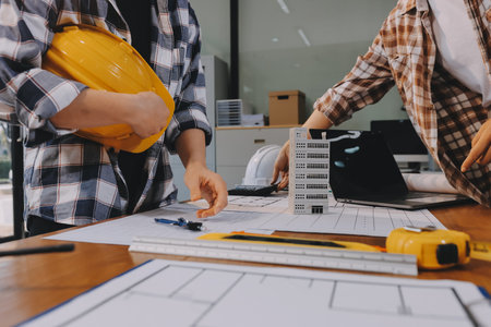 Construction and structure concept of engineer working drawing on blueprint meeting for project working with partner on model building and engineering tools in working site, construction concept.の写真素材